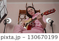Young woman plays guitar performs in strumming style that is characteristic of Spanish six string acoustic guitar. Performance in home studio of musician. Video is shot low angle and is handheld Young woman plays guitar performs in strumming style that is characteristic of Spanish six string acoustic guitar. Performance in home studio of musician. Video is shot low angle and is handheld 130670199