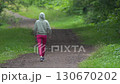 Full length view of slender woman doing warm up exercises. Unrecognizable fitness model in sports clothes walking on path in park during sports training, physical activity outdoors. Rear view, zoom in Full length view of slender woman doing warm up exercises. Unrecognizable fitness model in sports clothes walking on path in park during sports training, physical activity outdoors. Rear view, zoom in 130670202