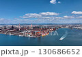 Drone footage of a vast coastal industrial area with rusty remains shining against the natural light of blue sea, blue sky, and white clouds. 130686652