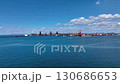 Drone footage of a vast coastal industrial area with rusty remains shining against the natural light of blue sea, blue sky, and white clouds. 130686653