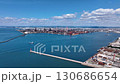 Drone footage of a vast coastal industrial area with rusty remains shining against the natural light of blue sea, blue sky, and white clouds 130686654