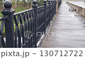 Black cast-iron railing on a pedestrian bridge. Walking on the bridge after it has rained. 130712722