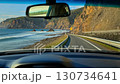 A view from inside a car driving along a winding road along the sea, with an exhilarating driving scene of the blue coastline 130734641