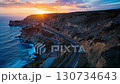 The bird's-eye view of the cliff coast and curving road bathed in the sunset creates a dynamic landscape that evokes the feeling of traveling to your destination. 130734643