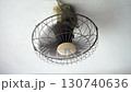 An old electric ceiling fan with a protective grill, designed for cooling and air circulation 130740636