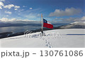 A long shot of the flag waving on a snowy mountaintop and the strait. A backdrop of nature and adventure. 130761086