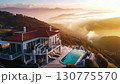 Luxury villa aerial view. A natural landscape with a building on a hill with a swimming pool overlooking the sunset, surrounded by sky, mountains, clouds, and light 130775570