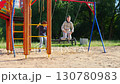 A group of children joyfully playing on swings at the lively playground during sunny day 130780983