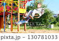 Children are joyfully playing on colorful swings at a vibrant playground filled with fun 130781033