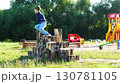 Children are joyfully playing on log stumps at a lively and engaging playground area, 130781105