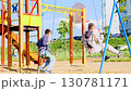 Joyful children play on swings in a sunny playground, filled with laughter and vibrant colors 130781171