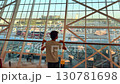 Teenager gazing out from the Baku airport with a view of the busy parking lot and terminal 130781698