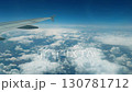Airplane wing extending over a vast expanse of fluffy white clouds against a bright blue sky, capturing the essence of travel 130781712