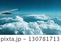 Airplane wing above fluffy white clouds against a bright blue sky, showcasing the beauty of flight and the vastness  130781713