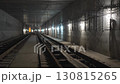 Rails stretch through long dim tunnel lined with hooks 130815265