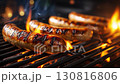 Sizzling sausages cooking on a flaming barbecue, showcasing vibrant grilling action sequence 130816806
