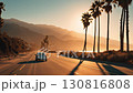White car cruising along an empty coastal highway with palm trees at sunset, showcasing scenic beauty 130816808