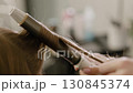 Hair curling. Hairdresser stylist make-up artist uses curling iron to curl hair. Close-up 130845374