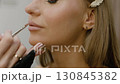Make-up artist, beauty salon concept. Makeup artist painting model lips with brush. Close-up 130845382