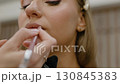 Makeup concept. Makeup artist outlines lips with pencil. Close-up 130845383