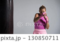 Woman power, pro fighter trains his beats, training in the white boxing gym, sporty woman in a pink cloth trains a series of punches, front view. 130850711