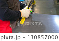 Metalworker using scriber and ruler to mark lines on metal sheet 130857000