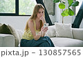 Upset sad young woman looking at smartphone sitting on couch at home 130857565