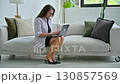 Serious middle aged woman typing on laptop, sitting on sofa 130857569