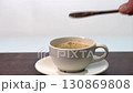 Adding 3 wooden spoons of brown sugar to hot black coffee in double wall clear glass cup 130869808