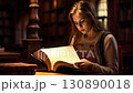 Young girl reading intently, warm library lighting casting soft glow on focused face while diving deep into absorbing literary narrative 130890018