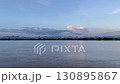 The Mekong River at sunset with calm water reflecting the pastel sky and glowing clouds, framed by a scenic mountain range. A tranquil landscape ideal for travel, nature, and background use 130895867
