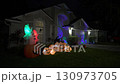 A suburban house is decorated with glowing pumpkins, ghosts, and Halloween lights at night. The spooky scene shows festive inflatables, colorful lights, and holiday spirit. 130973705
