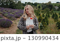Portrait of blonde woman wearing casual clothes, standing amid vibrant lavender field, gently holding poppy flower and experiencing serene moment of tranquil countryside landscape. Portrait of blonde 130990434