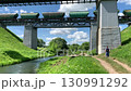 A train carrying freight cars travels across a bridge over a river. 130991292