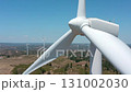 Wind turbine blades rotating against clear blue sky, revealing renewable energy generation across expansive wind farm landscape, capturing sustainable power production in natural setting 131002030