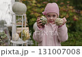 Child enjoys fall harvest with colorful gourds in beautiful outdoor setting 131007008