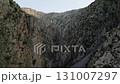 Uzbekistan mountain gorge at dawn with sheer cliff wall and green ravine 131007297