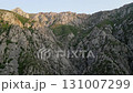 Uzbekistan highland ridge above deep limestone gorge with greenery and sunrise 131007299