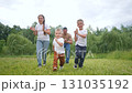 The boy claps in joy, the girl claps in joy, the child claps in joy, father claps in joy while playing the game on green grass. Kids share happiness, fun, laughter, running together in the sunny field 131035192