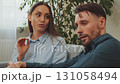 Angry couple sitting on couch during conflict, woman speaking emotionally while man listens silently showing relationship tension 131058494