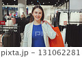 Happy young woman walking in clothing store with bright shopping bag, smiling at camera and enjoying modern fashion retail experience 131062281