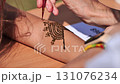 Artist drawing henna tattoo on woman arm in India 131076234