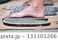 Woman practicing acupressure by placing foot on sadhu board in India 131101266