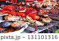 Street food vendor preparing grilled vegetables and meat skewers 131101316