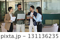 Businesspeople discussing data standing in modern co-working office 131136235