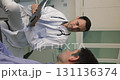 Happy male doctor talking to healthy patient, discussing examination results 131136374