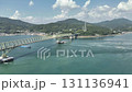 Bridge connecting Honshu and the island, shot from an oblique angle, commercial ships passing under the bridge, drone aerial shot 131136941