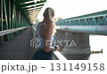 Woman runner rests on bridge after morning jog, sporty woman back view, slow motion, half-marathon training. 131149158