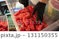 Person wearing gloves places sliced watermelon pieces into a container during the street food festival 131150355