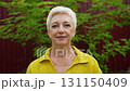 Closeup Portrait of Senior Woman Looking at Camera, Beautiful Face, Smiling. Elderly Lady with Natural Grey Hair, Blue Eyes. Abstract Beige Background, Tender and Soft Slow Motion 131150409